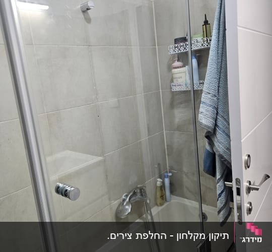 מקלחת עם דלת זכוכית ומגבת תלויה